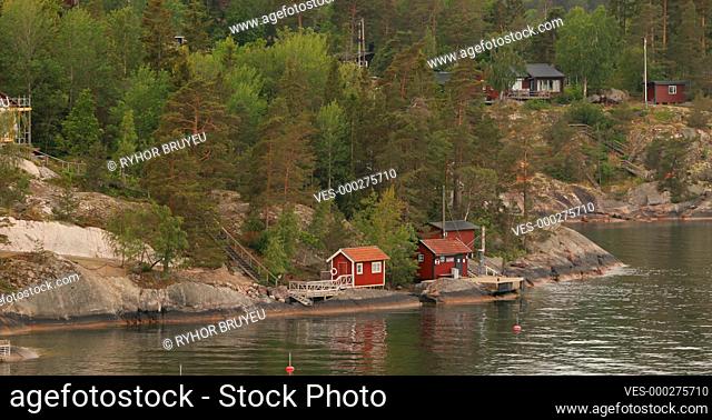 Many Swedish Wooden Sauna Logs Cabins Houses On Island Coast In Summer Cloudy Day