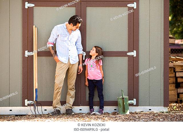 Girl looking at father in front of community garden shed