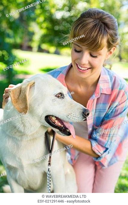 Pretty smiling blonde posing with her labrador in the park