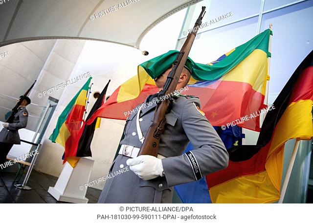 30 October 2018, Berlin: The flag of Ethiopia blows through the face of a Bundeswehr soldier of the guard battalion in front of the Federal Chancellery