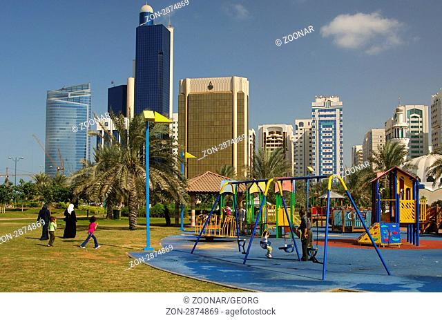 Kinderspielplatz vor der Skyline von Abu Dhabi, Vereinigte Arabische Emirate / Playground in front of the skyline of Abu Dhabi, United Arab Emirates