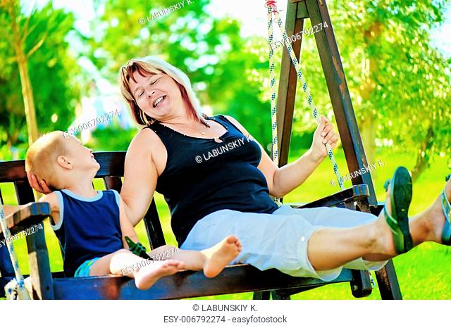 Happy grandmother and grandson on a swing