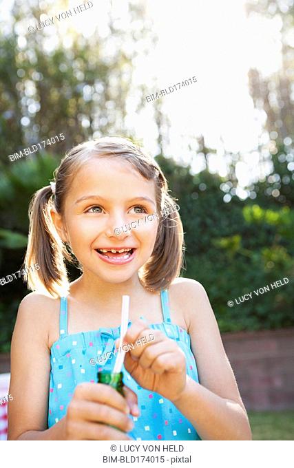 Smiling girl eating candy cigarette in backyard