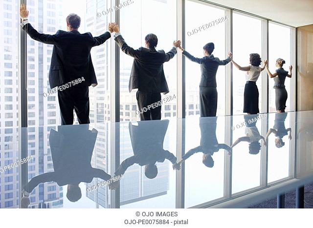 Business people standing at conference room window holding hands