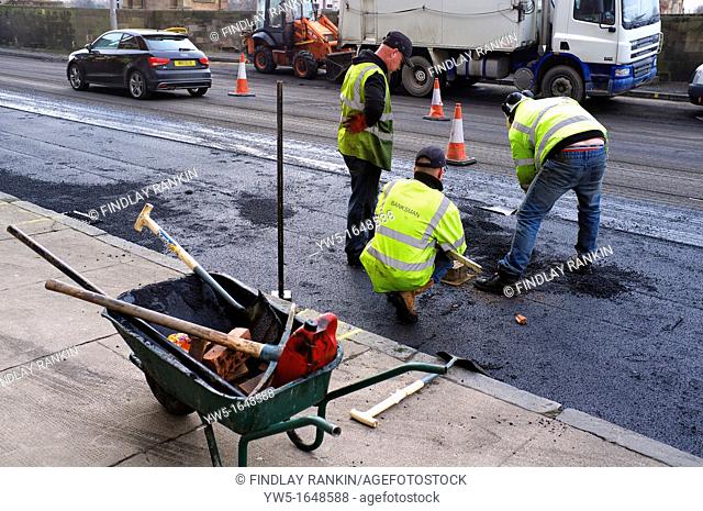 Three workmen repairing the road surface damage with potholes and water erosion, Glasgow, Scotland, UK, Great Britain