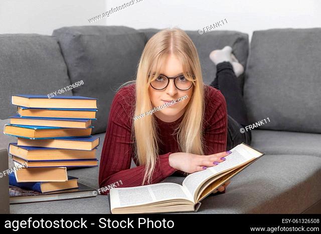 Self education concept. Young woman is lying against the camera and reading a book