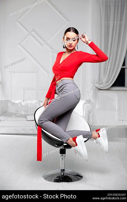 Young lady wearing a a red blouse and jeans posing in the studio