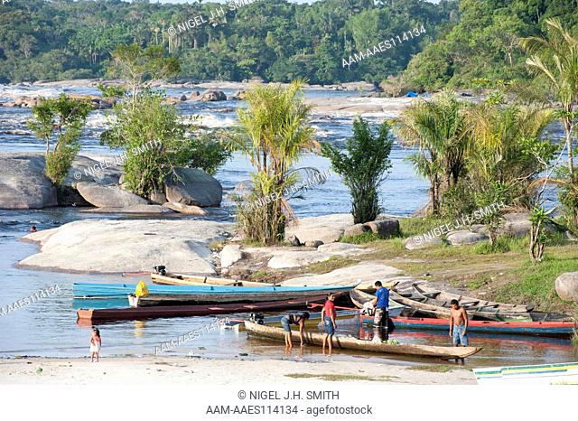 Rabetas and canoes at port by granite boulders. One rabeta has just arrived with a stalk of bananas. Sao Gabriel da Cachoeira, Rio Negro, Amazonas, Brazil