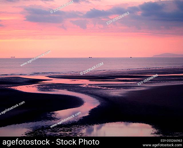 OLYMPUS DIGITAL CAMERAtwilight view of a dark beach with a pink sky after sunset with blue clouds reflected in the water at low tide and a calm sea in blackpool...