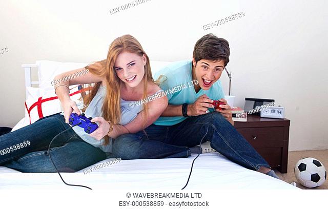 Boy and girl teens playing video games in a bedroom