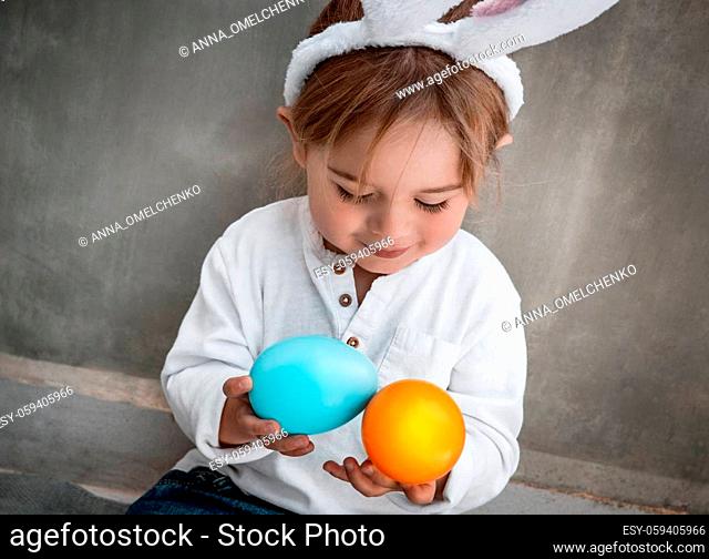 Cute Little Baby Dressed as Festive Bunny Playing with Colorful Eggs. Enjoying Happy Easter Holiday. Great Christianity Holiday