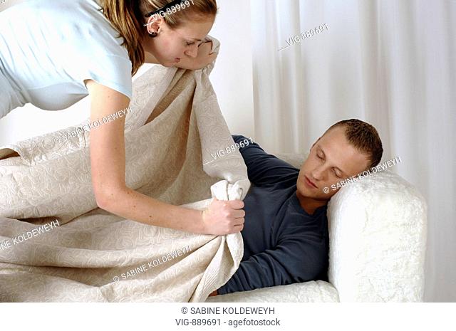 Young woman carpets her sleeping boyfriend on a sofa. - 30/06/2008