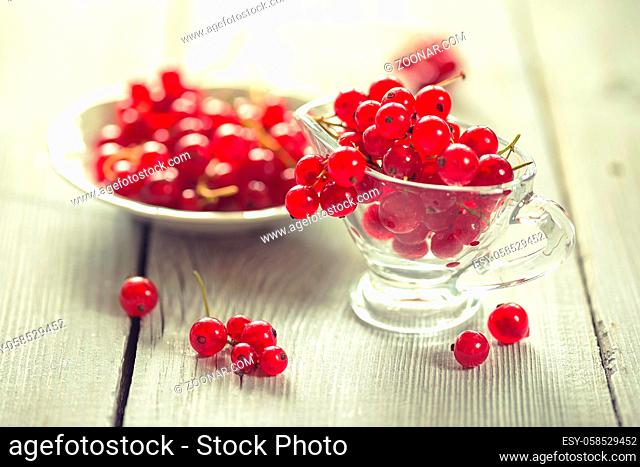 Fresh red currant on white wooden table. Cross processed color tone - retro style filtered image