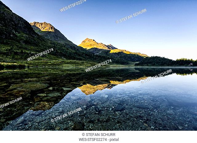 Austria, East Tyrol, Shiny lake reflecting mountains in Defereggen Valley