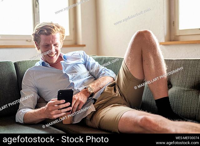 Happy man using mobile phone while sitting at home