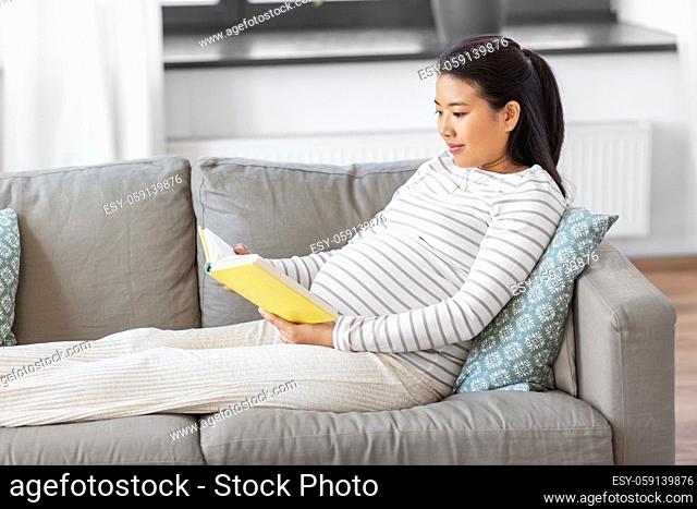 happy pregnant woman reading book at home