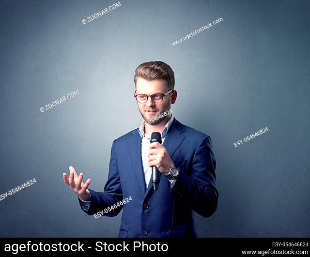 Businessman speaking into microphone with blue background