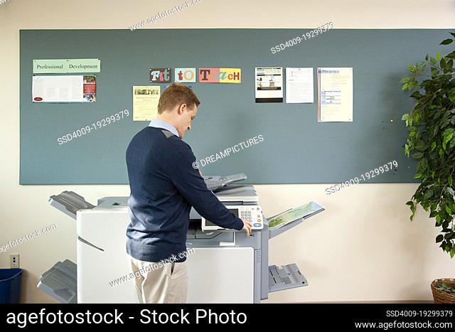Caucasian man making copies at printer in office