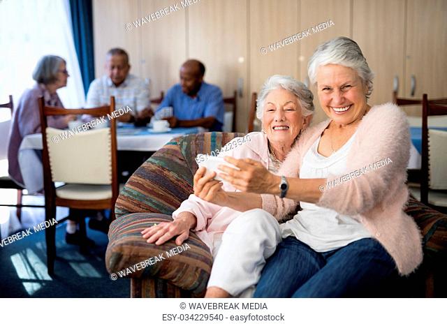 Portrait of smiling senior woman taking selfie with friend