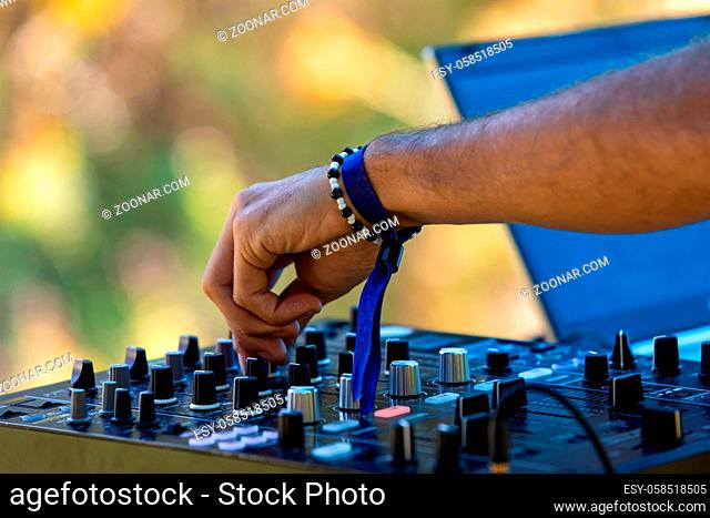 A close up selective focus view on the hands of a music DJ at work during a festival celebrating culture, acoustic sounds and alternative communities