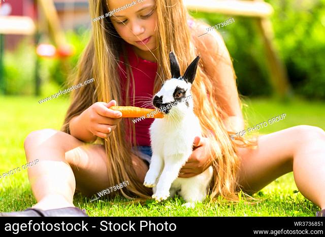 Happy Girl or daughter with her rabbit or bunny pet at home in the garden