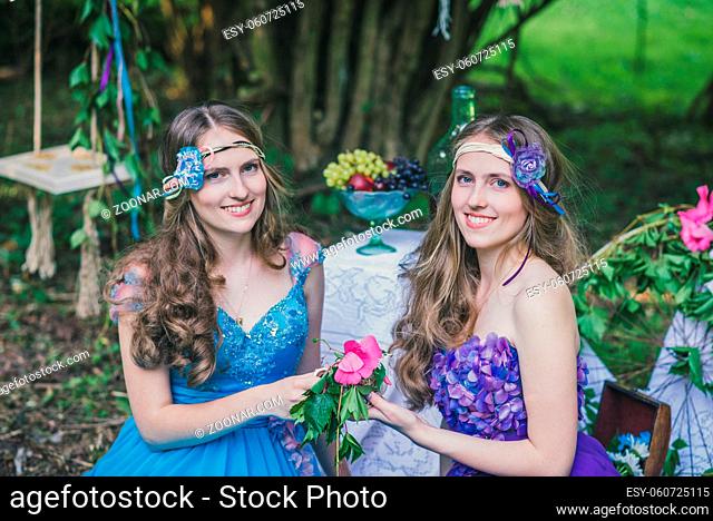 two adult sisters are twins with flowers in the summer garden