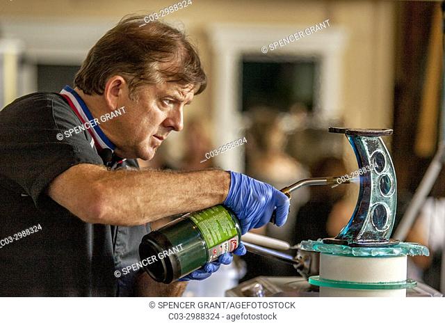 A French master chocolatier uses a propane torch to assemble molded components of a sugar sculpture at a food demonstration in Costa Mesa, CA