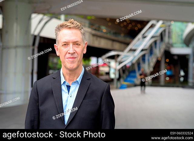 Portrait of mature businessman in suit at footbridge in the city