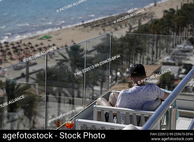 PRODUCTION - 11 May 2022, Spain, Palma: A customer relaxes on the roof terrace of the Iberostar Bahia de Palma hotel on Arenal beach in Mallorca
