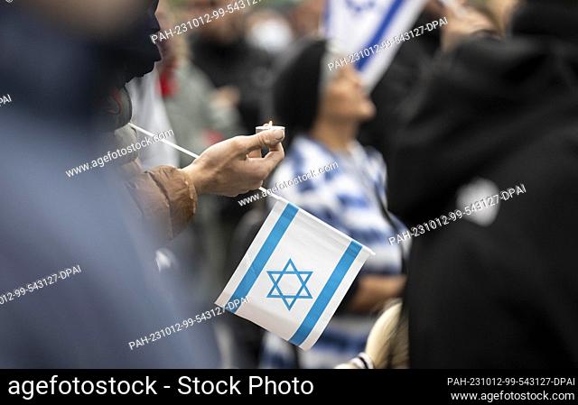 12 October 2023, Saxony, Leipzig: A participant of a rally in the center of the city holds a candle and an Israeli flag in his hand