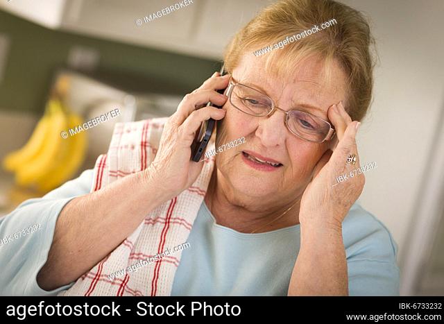 Shocked senior adult woman on her cell phone in kitchen