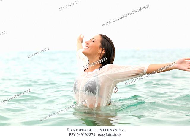 Joyful woman stretching arms in the sea water on the beach