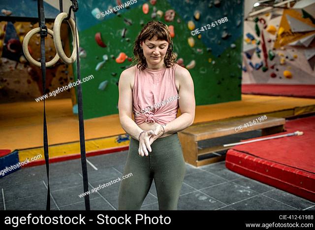 Young woman chalking hands at rock climbing wall