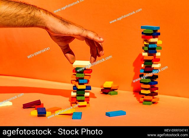 Man stacking toy blocks against orange background