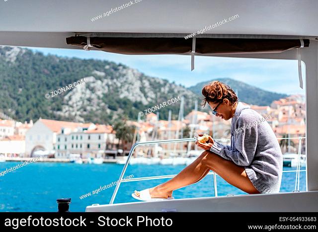 Vacation, holidays, travel, sea and people concept - smiling young woman sitting on yacht deck
