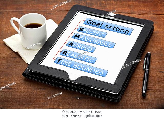 SMART specific, measurable, agreed, realistic, time bounded goal setting concept - a diagram on a tablet computer with stylus pen and espresso coffee cup...