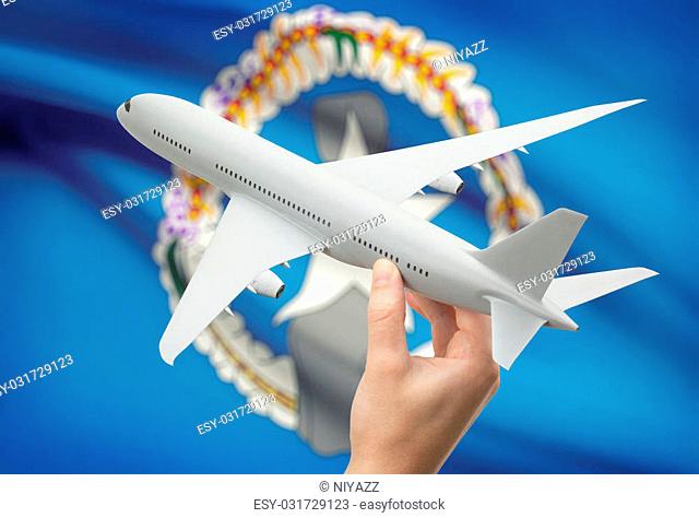 Airplane in hand with national flag on background - Northern Mariana Islands
