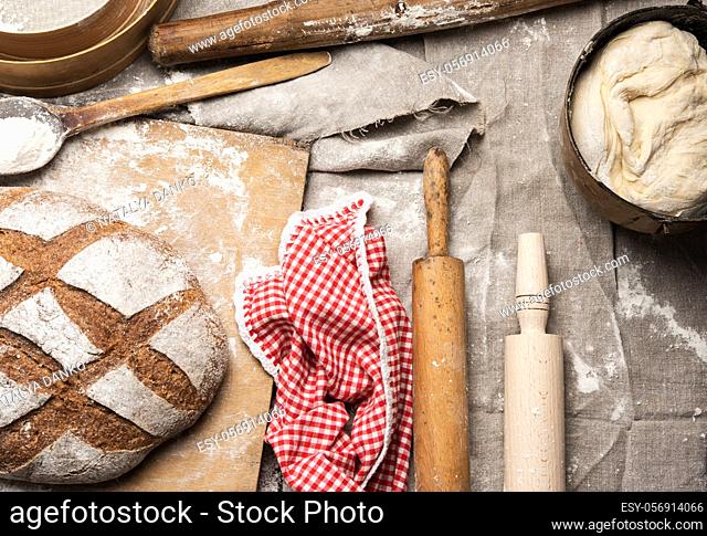 bread, kneaded dough of white wheat flour lies on a metal bucket and a wooden rolling pin, top view
