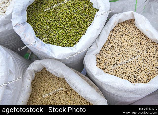 Rolled up sacks full of legumes. Mung beans, lentils and black-eyed peas. Displayed at street market stall