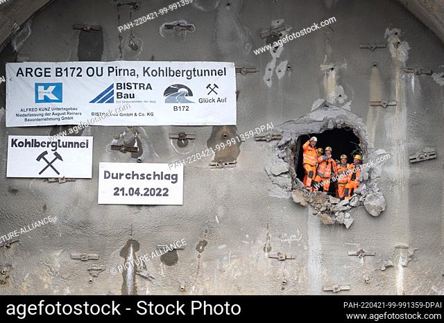 21 April 2022, Saxony, Pirna: Construction workers stand in an opening of the 300-meter-long Kohlberg Tunnel during the breakthrough