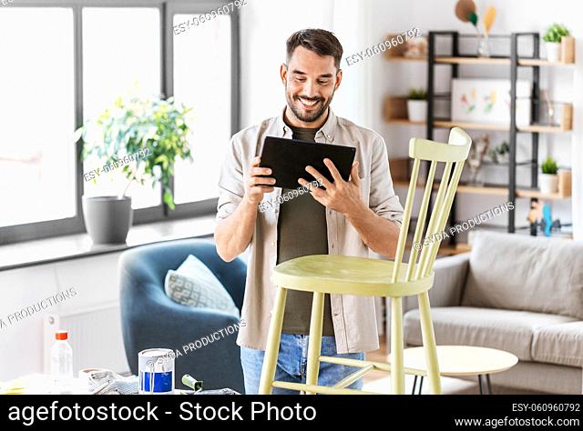 man with tablet pc renovating old chair at home
