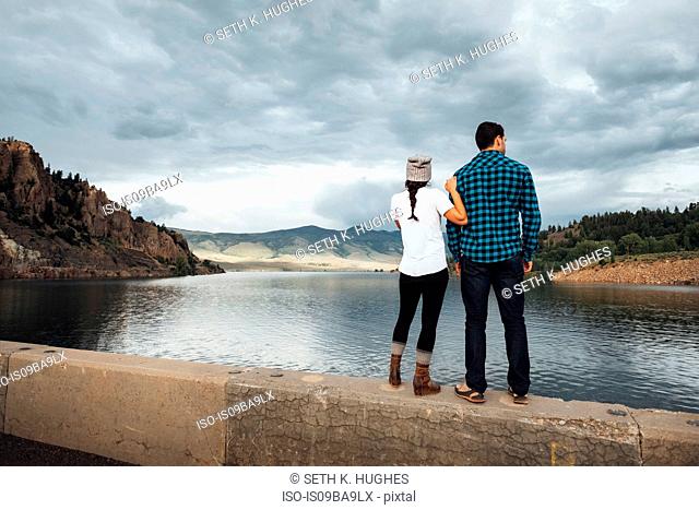 Couple standing on wall beside Dillon Reservoir, looking at view, rear view, Silverthorne, Colorado, USA