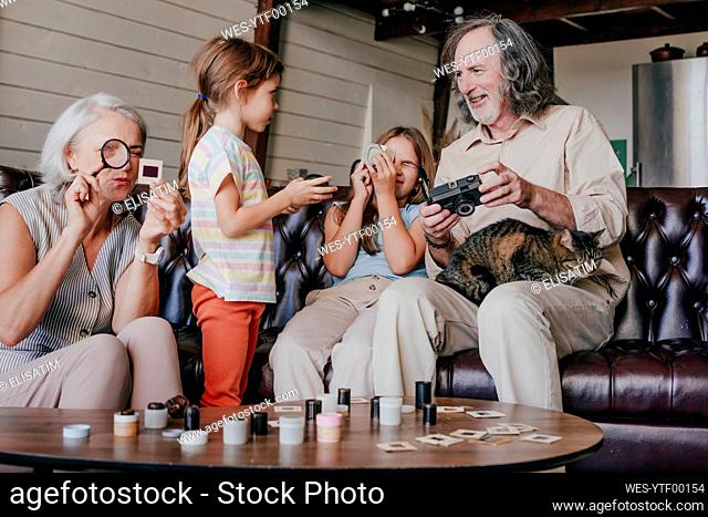 Granddaughters with grandparents looking at vintage film camera and film slides