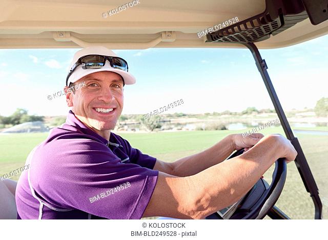 Portrait of smiling Hispanic man driving golf cart