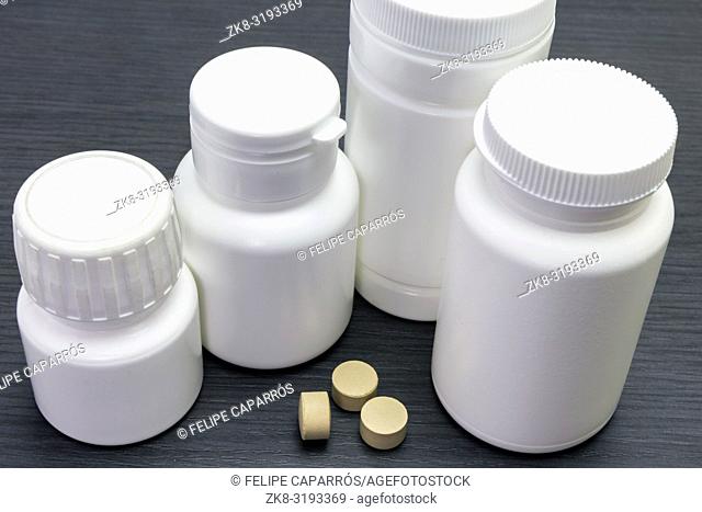 white bottles of pills of different sizes, conceptual image