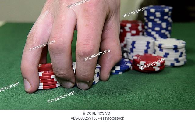 Poker player fiddling with a stack of red and white chips
