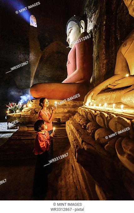 Asian mother and daughter lighting candles in temple
