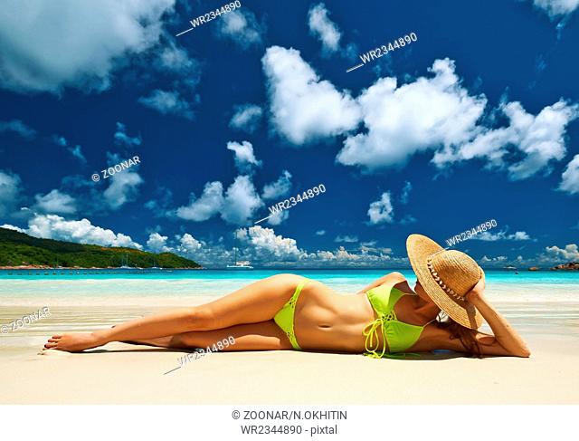 Woman in yellow bikini lying on beach at Seychelles