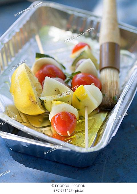 Vegetable kebabs in aluminium dish with oil and brush