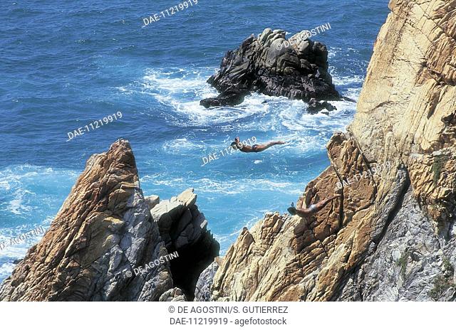 Divers jumping off the cliff called La Quebrada, Acapulco, Mexico